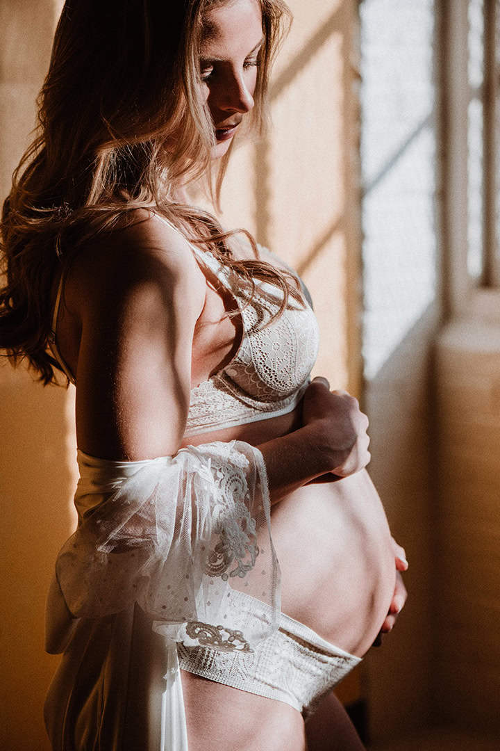 Expecting mother wearing an oversized shirt during a modern maternity boudoir session.