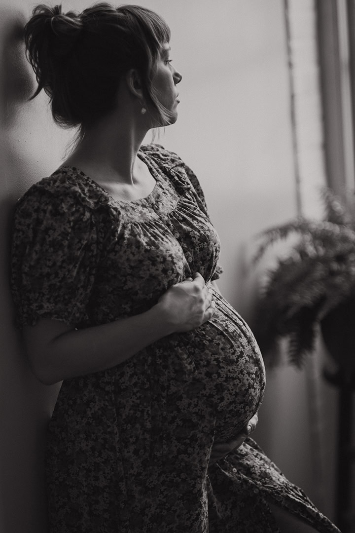 Pregnant woman wearing a soft, vintage floral maternity outfit during a maternity boudoir photography session.