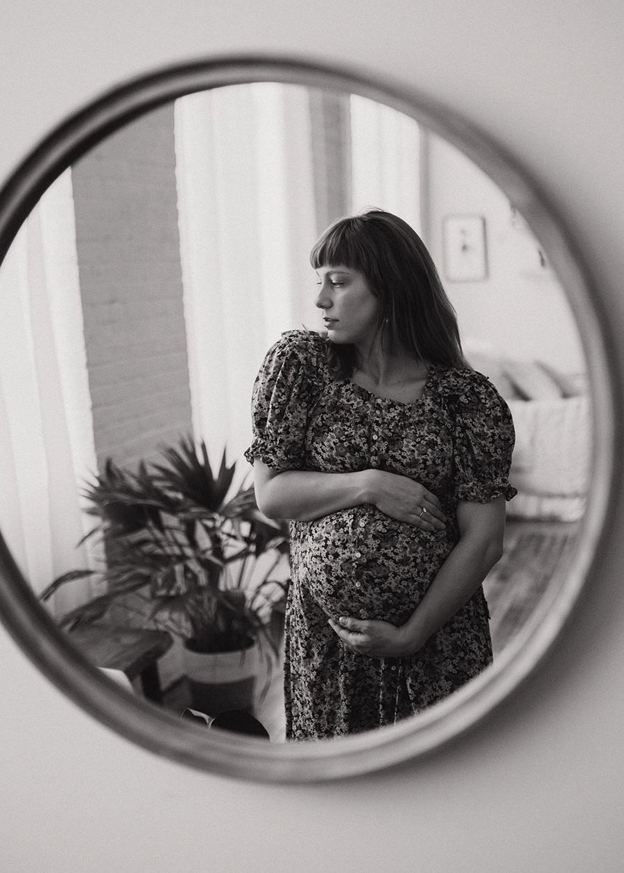 Pregnant woman wearing a soft floral maternity outfit during a maternity boudoir photography session.