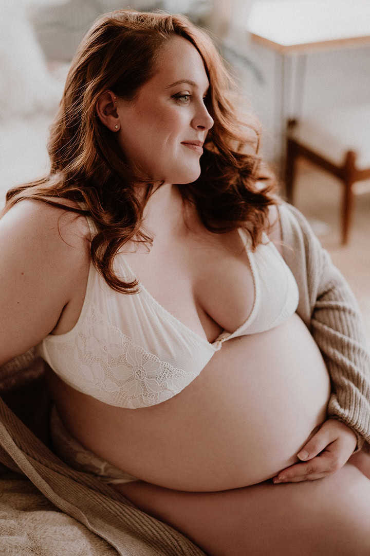 Alt Text Pregnant woman relaxing in white lingerie during a maternity boudoir photography session in Connecticut.