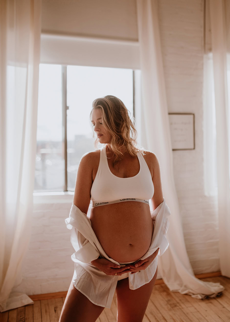 Expecting mother wearing an oversized shirt and calvin kleins during a modern maternity boudoir session.