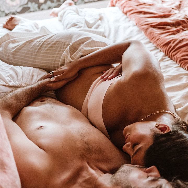 Expecting couple embracing on a bed during a lifestyle maternity photography session in Connecticut.