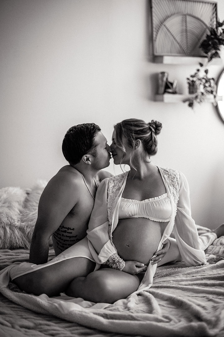 Expecting couple sharing an intimate moment during a cozy maternity boudoir session.