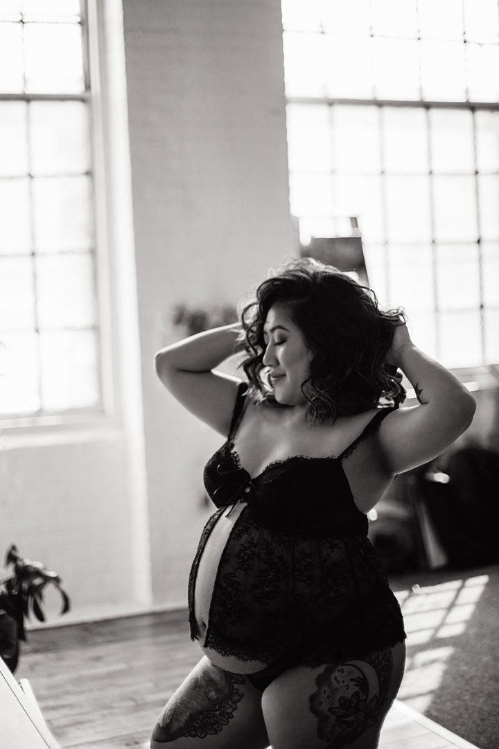 Expecting mother posing in natural light during a black-and-white maternity boudoir session in Connecticut.
